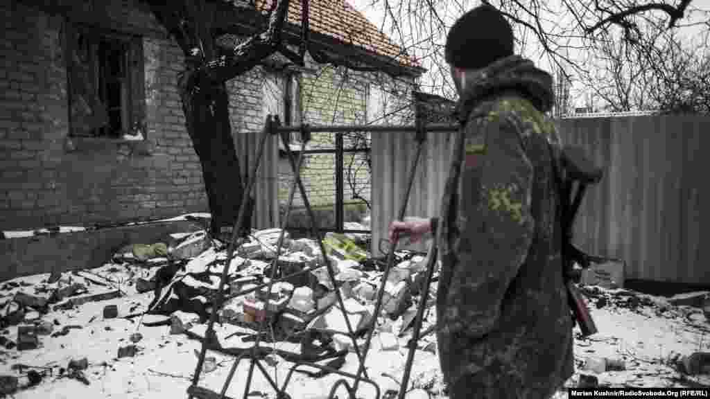 Пустая качеля Стахановца. Солдат Вооруженных сил Украины качает пустое место. Если развернуться, то на горизонте виднеются укрепления поддерживаемых Россией сепаратистов. Вокруг качели – полуразрушенные здания