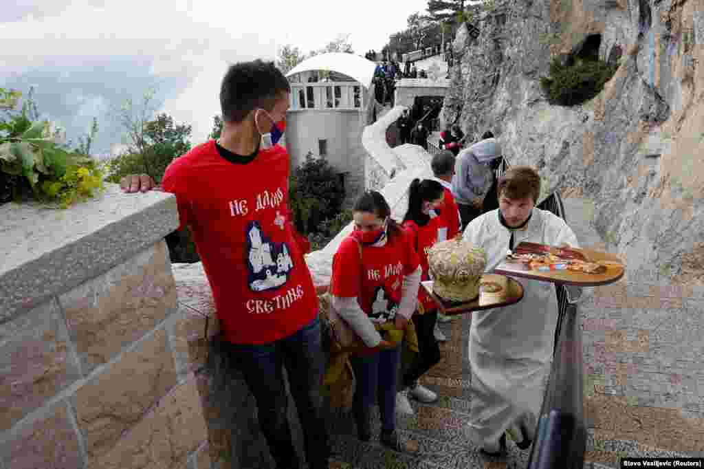 Sveštenik prolazi pored vernika sa zaštitnim maskama ispred Crkve Svetog Vasilija Ostroškog u Nikšiću u Crnoj Gori, 12. maj 2020. godine. 