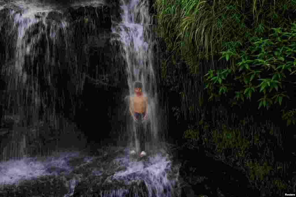 Мальчик охлаждается под водопадом на окраине Совари в округе Бунер в провинции Хайбер-Пахтунхва, Пакистан, 20 августа 2025 года. REUTERS/Akhtar Soomro