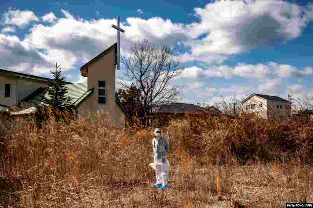 Sveštenik Akira Sato u zaštitnom odelu ispred stare zgrade Baptističke crkve u Tamioki, području koje je proglašeno zonom koja nije za život 2011. godine. Deset godina nakon katastrofe crkva je samo prazna ljuštura.