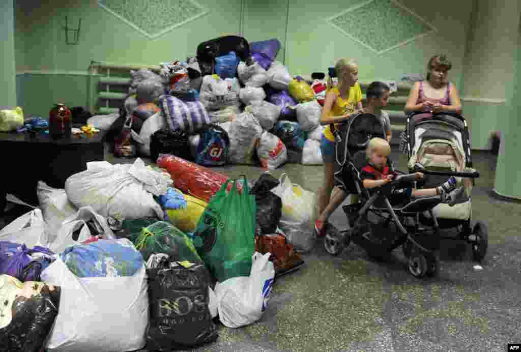 Дети стоят рядом с личными вещами тех, кто бежал из районов Донбасса, где продолжаются боевые действия. Эта фотография сделана в городе Иловайск Донецкой области: все административные здания и гостиницы здесь отданы на нужды перемещенных лиц 