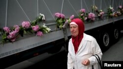 A woman cries near a truck carrying coffins of newly identified victims of the 1995 Srebrenica massacre, in Sarajevo, July 9, 2015.