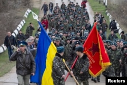 Українські вояки із прапорами і виконанням державного Гімну України на підході до російських військових, які відкрили попереджувальний вогонь. Крим, Бельбек, 4 березня 2014 року