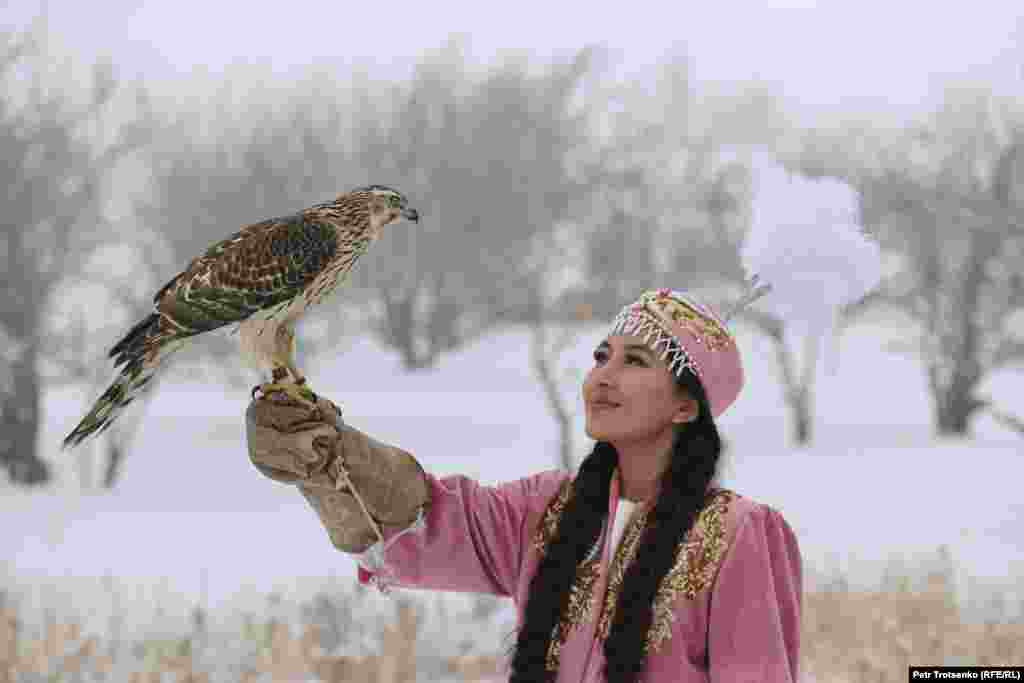 Дівчина в національному вбранні тримає на руці хижого птаха