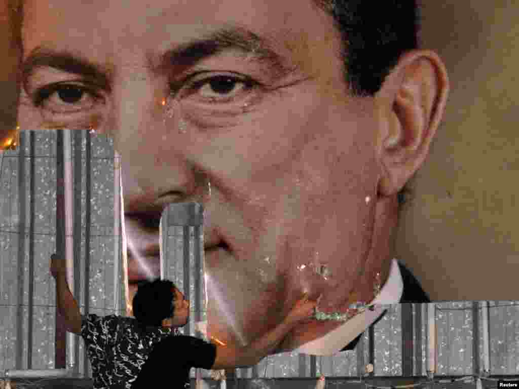 Протестующий срывает портрет президента Хосни Мубарака в Александрии