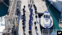 Мигранти придружувани од италијанската полиција во пристаништето Шенѓин, северозападна Албанија, на 28 јануари 2025 година.