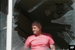 Un bărbat privește geamul spart al apartamentului său după atacul rusesc, la Kiev, pe 4 iulie 2025.
