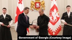 მიხეილ ყაველაშვილი მირზა კეზევაძეს აჯილდოვებს.