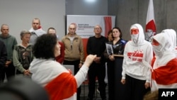 Exiled Belarusian opposition leader Svetlana Tikhanovskaya (3rdR) looks on as she stands next to members of the Belarusian Volny Chor (R) performing during a press conference with freed political prisoners, among them Belsat journalist Iryna Slaunikava (2