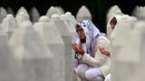 Боснийские мусульманки молятся у могил своих родственников на мемориальном кладбище в Сребренице