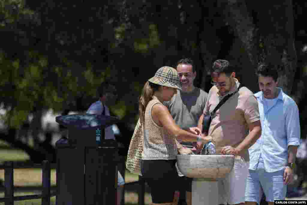 Njerëz duke mbushur shishe me ujë në një krua në Lisbonë, më 29 qershor.