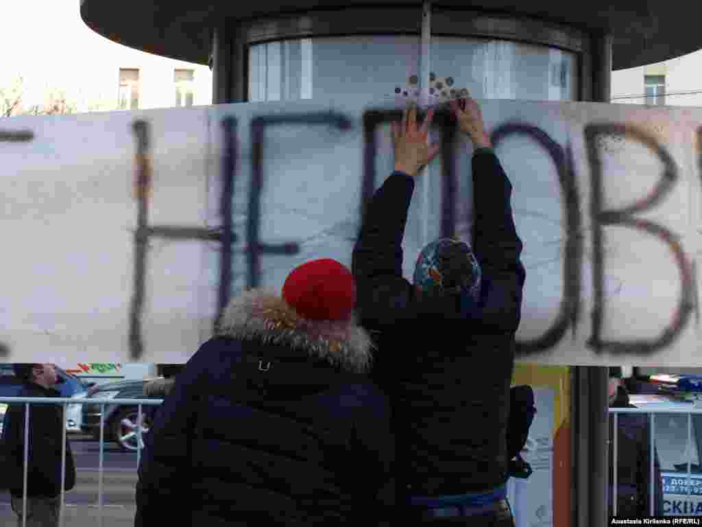 Молодые люди закрепляют растяжку с надписью "неповиновение"