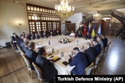 Delegațiile rusă, stânga, și ucraineană, dreapta sus, se întâlnesc împreună cu observatorii Națiunilor Unite și cu membrii Ministerului turc al Apărării la Istanbul, Turcia, 13 iulie 2022, în încercarea de a ajunge la un acord asupra unui plan al Națiunilor Unite de a exporta cereale ucrainene blocate pe piețele mondiale prin Marea Neagră.