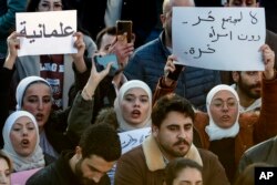 Sirijske žene uzvikuju slogane dok drže plakate na arapskom na kojima piše: "Ne za slobodno društvo bez slobodne žene", desno, i "Sekularizam", lijevo, tokom protesta za traženje sekularne države, na trgu Omajada u Damasku, Sirija , 19. decembar 2024.