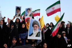 Демонстранты держат флаги Ирана и плакаты с изображением Верховного лидера аятоллы Али Хаменеи на антиизраильском и антиамериканском митинге на площади Энкеляб-е-Эслами (площади Исламской революции) в центре Тегерана, 24 июня 2025 года