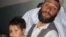 An Afghan man holds a child reportedly injured in an ISAF air strike in Herat Province on July 17