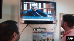 Iraqis watch a state television broadcast in Baghdad in 2010.