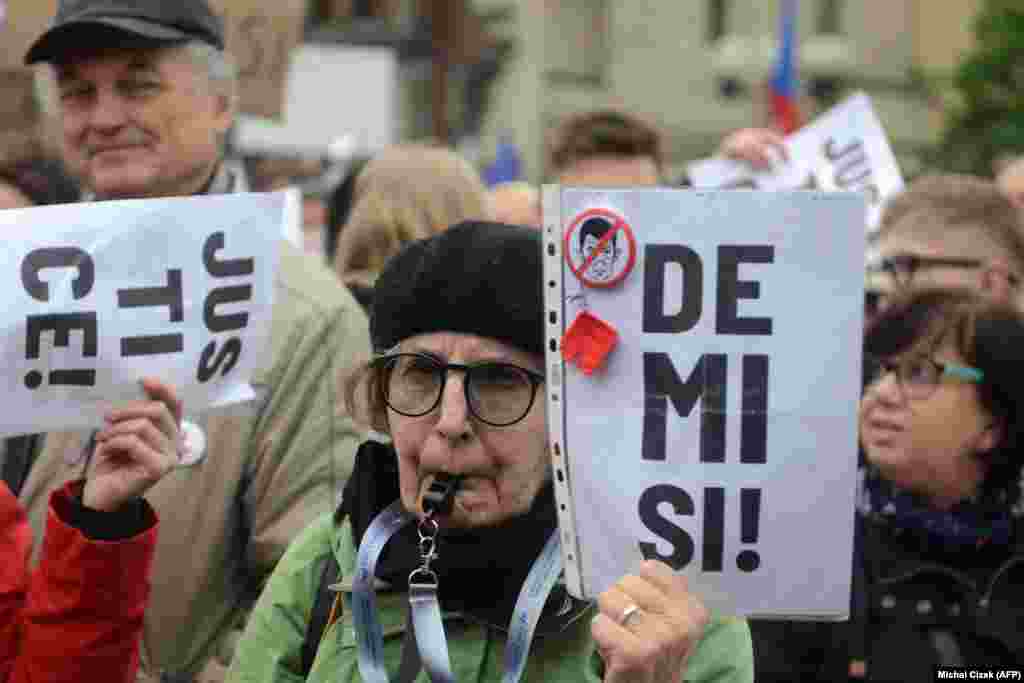 Жінка свистить у свисток та тримає баннер, на якому написано: «Відставка»