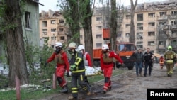 პარამედიკოსებს და მაშველს დაღუპულის ცხედარი გააქვთ კიევზე რუსეთის სარაკეტო დარტყმის ადგილიდან. 2025 წლის 24 აპრილი 