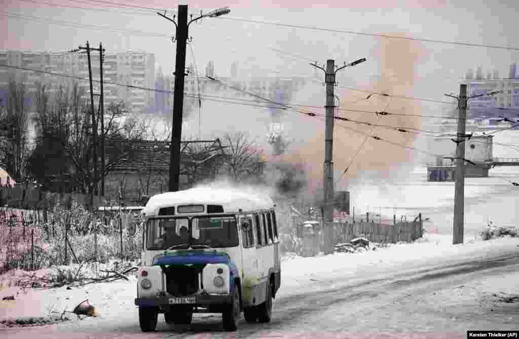 Autobus prolazi, dok se dim diže iz zgrade koju su 24. januara 1995. godine više puta pogodile tenkovske granate na jugozapadu Groznog