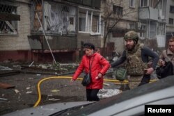 Ukrajinske službe evakuišu ženu iz stambene zgrade pogođene u ruskom raketnom napadu u Sumi, Ukrajina, 24. marta.