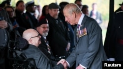 Regele Charles dând mâna cu un veteran la ceremonia de luni.