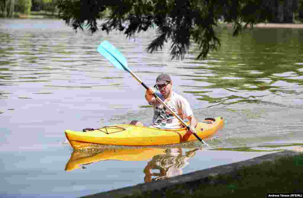 Un bărbat se plimbă cu caiacul pe lacul din Parcul Alexandru Ioan Cuza din București.