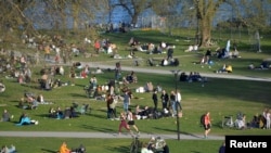 Ljudi u parku uživaju u suncu u Stokholmu, 22. april