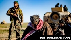 Muškarci za koje se sumnja da su borci takozvane Islamske države čekaju pretres pripadnika Sirijskih demokratskih snaga (SDF) predvođenih Kurdima nakon što su 1. marta 2019. napustili poslednje uporište u gradu Baguzu.