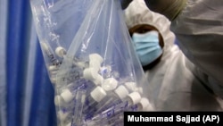 A health official in protective gear holds samples collected from people at a screening and testing facility for COVID-19 in Peshawar. (file photo)