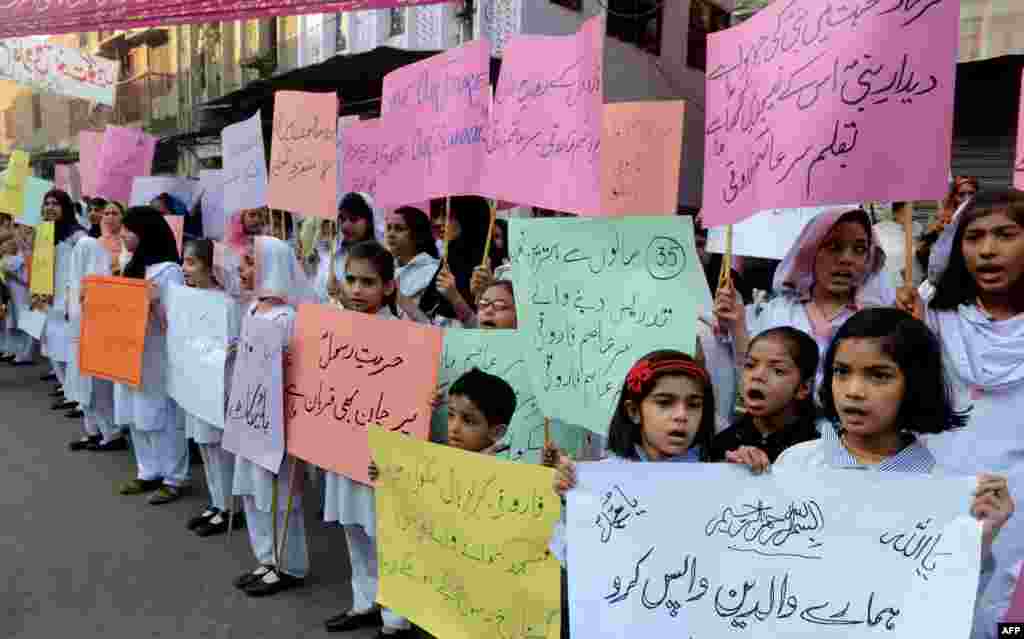 Students of Farooqi Girls' High School wave placards as they stage a protest in Lahore on November 3, demanding the reopening of their school after it was set on fire by an angry mob that alleged the school gave a test that insulted the Prophet Muhammad.