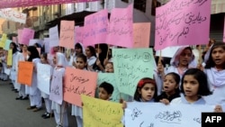 Pakistani students of Farooqi Girls' High School wave placards as they stage a protest in Lahore on November 3, demanding the reopening of their school after it was set on fire by an angry mob.