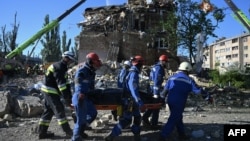 Украинские спасатели несут тело жертвы, найденное во время поисково-спасательной операции на месте жилого дома, сильно поврежденного в результате удара РФ в Киеве, 28 августа 2025 года