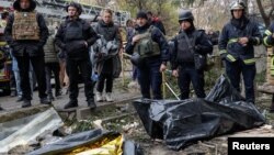 Police officers stand next to the bodies of people found under the debris of an apartment building that was hit by a Russian air strike in Kharkiv on October 31.