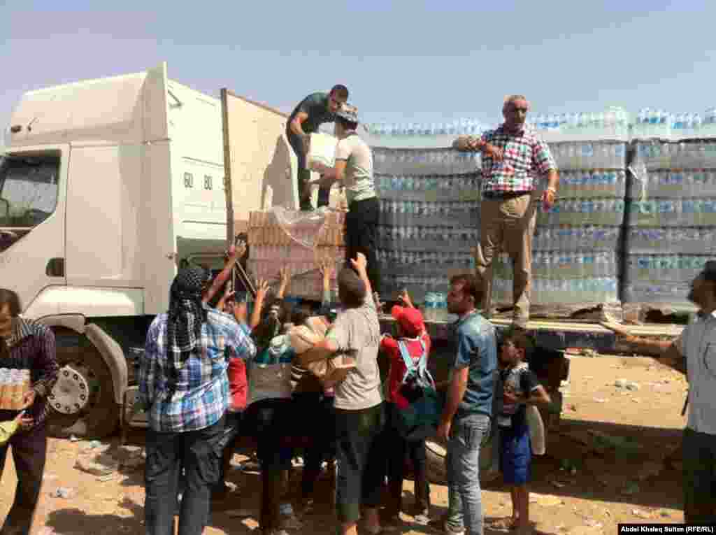 Refugees receive food and water in the border village of Sihela, in Iraq's autonomous Kurdish region.
