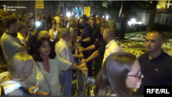 Učesnici protesta "1 od 5 miliona" sa leve i pripadnici vojnog obezbeđenja (u civilu) sa desne strane zaštitne ograde tokom protesta u subotu 10. avgusta