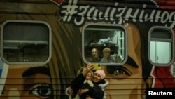 Stanovnici Hersona ispred prvog voza od početka invazije koji je stigao u grad na jugu, 19. novembra 2022.