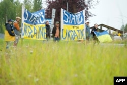 Protestatarii flutură steaguri ucrainene în fața bazei militare Elmendorf-Richardson în timpul întâlnirii dintre președintele american Donald Trump și președintele rus Vladimir Putin la Anchorage, Alaska, pe 15 august 2025.