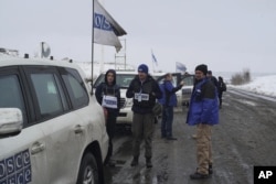 Асистент з питань безпеки ОБСЄ Вадим Голда (в центрі) стоїть біля свого автомобіля під час патрулювання в Донецькій області України, 23 листопада 2017 року