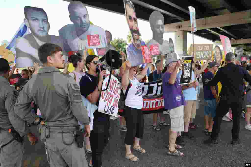 Demonstranti mašu transparentima sa slikama talaca, dok blokiraju cestu tokom demonstracija koje su organizirale porodice izraelskih talaca, u Tel Avivu 26. avgusta 2025. godine.
