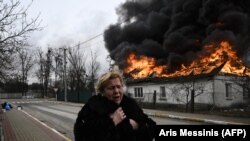 Жінка біля будинку, що горить після обстрілу в час масштабного вторгнення Росії до України. Місто Ірпінь Київської області, 4 березня 2022 року