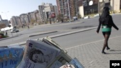 Kosovo -- A money changer displays a handful of different currencies, Pristina, 11Nov2008