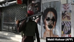 Talibanski borac prolazi pored salona za ljepotu na kojem je sprejem išaran ženski lik na fotografiji, Kabul, 18. avgust 2021.