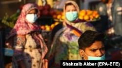 People wearing face masks walk through a market in Karachi. (file photo)