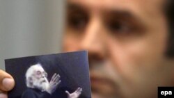 Rasim Ljajić, predsednik Nacionalnog saveta za saradnju sa Haškim tribunalom, drži fotografiju na kojoj je Radovan Karadžić