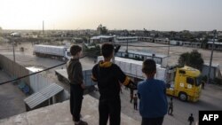 ბიჭები თვალს ადევნებენ სატვირთო მანქანებს, რომლებსაც ღაზის სექტორში ჰუმანიტარული დახმარება შეაქვთ. რაფაჰი, 26 ნოემბერი, 2023.