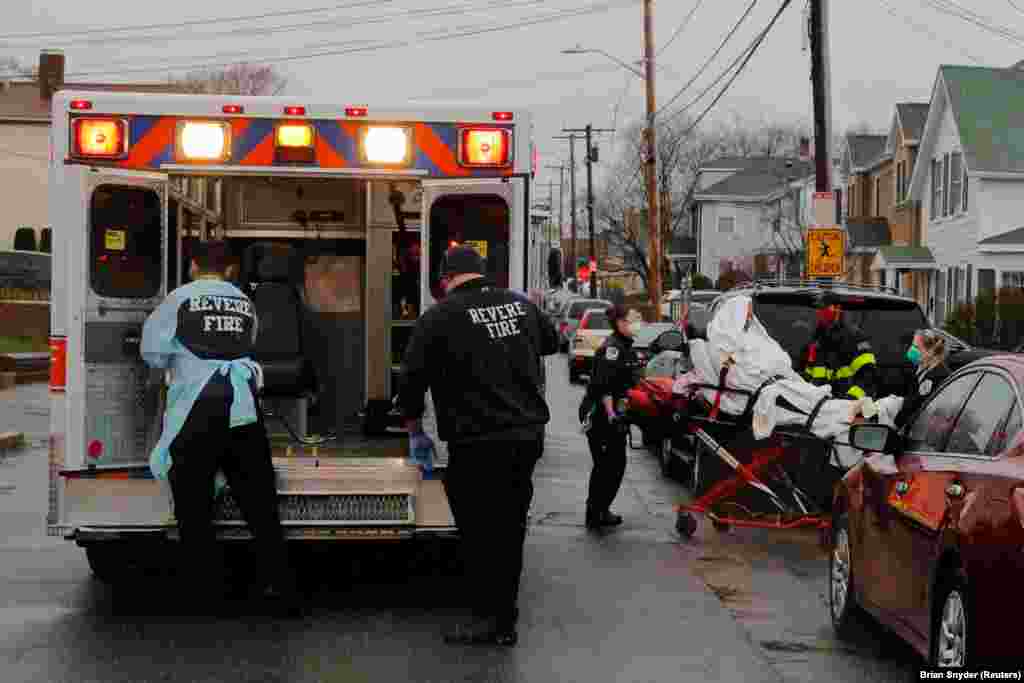 Medics and firefighters bring a patient to the ambulance amid the coronavirus disease (COVID-19) outbreak in Revere, Massachusetts, U.S.