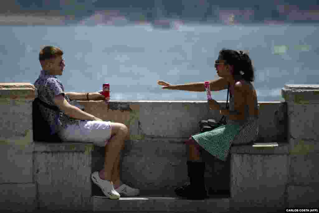 Dy të rinj duke u freskuar me pije e me akullore pranë lumit Tagus, në Lisbonë, më 29 qershor.