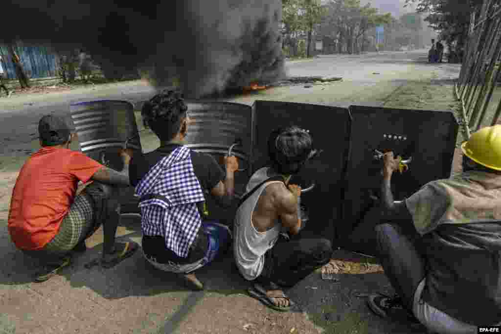 Демонстранты прячутся за металлическими щитами в районе Хлаинг Тарьяр города Янгон, Мьянма, 14 марта 2021  