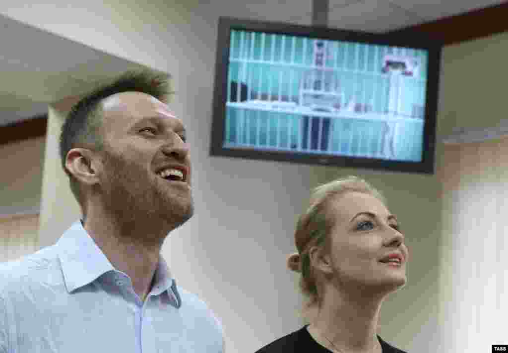 Алексей Навальный и его супруга Юлия во время слушаний по апелляции на приговор по делу "Ив Роше". На экране - брат Алексея Олег, который приговорен к реальному сроку. 17 февраля 2015 года. 
